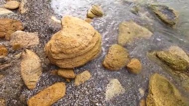 Beyaz köpüklü şeffaf su dalgaları kumların üzerinde akıyor.