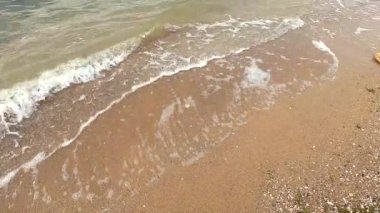 Beyaz köpüklü şeffaf su dalgaları kumların üzerinde akıyor.