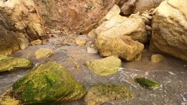 Beyaz köpüklü şeffaf su dalgaları kumların üzerinde akıyor.