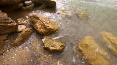 Beyaz köpüklü şeffaf su dalgaları kumların üzerinde akıyor.