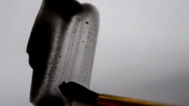 Erkek sanatçı, siyah boya suluboya fırça darbeleriyle resim yapar.