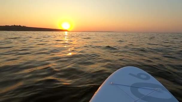 Man on paddle board floats in sea at sun dawn. POV. Slow motion — Stock Video