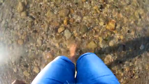 Fille marche pieds nus sur un fond sablonneux avec des pierres du rivage de la mer — Video