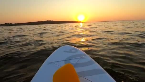 Mannen på paddelbrädet flyter i havet i soluppgången. Födelsedatum: Långsamma rörelser — Stockvideo