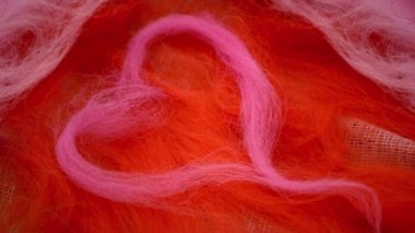 Pembe kalp yünü kırmızı bir yün üzerine serilmiştir.