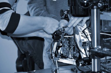 İki erkek usta atölyede elektronik, kablo ve 3D yazıcıda çalışıyor..