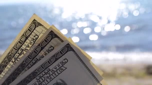 Долларовые купюры на фоне моря в солнечный день крупным планом. — стоковое видео