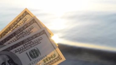 Deniz yüzeyinin arka planında 300 dolarlık banknotlar. 100 dolar nakit.