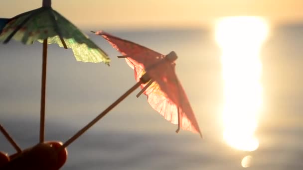 El hombre tiene en la mano un cóctel de playa pequeños paraguas de papel primer plano. — Vídeos de Stock