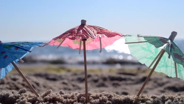 夏日明媚的近照，海滨沙滩上的纸制鸡尾酒雨伞 — 图库视频影像