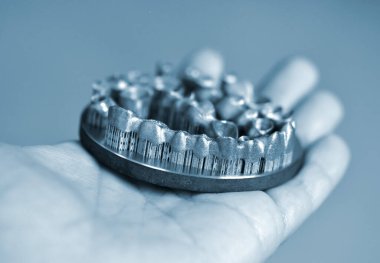 Metal 3D yazıcıya yazdırılmış nesneyi tutan adam.