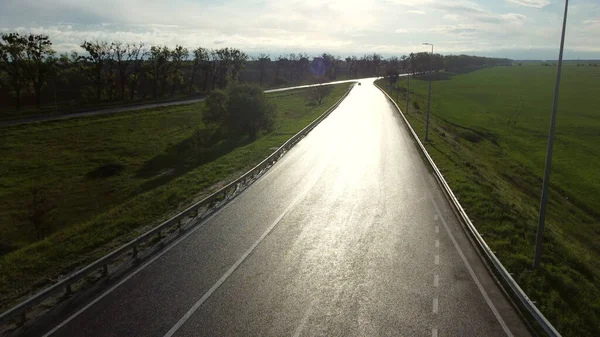 파종 된 밭 사이 의차가 다닐 수있도록 축축 한 아스팔트 도로 위에 있는 드론 — 스톡 사진