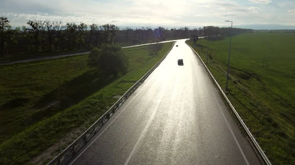 Drone above wet asphalt road for cars between sown fields — Stock Photo, Image