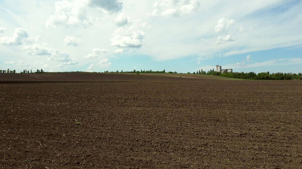 Воздушный беспилотник видит полет над огромным вспаханным полем и голубым небом.