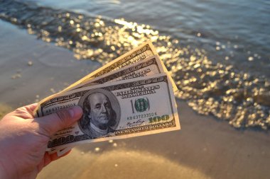 Deniz yüzeyinin arka planında 300 dolarlık banknotlar. 100 dolar nakit..
