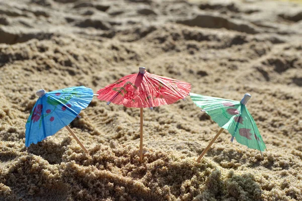 Pequenos guarda-sóis de praia feitos de papel para coquetel na areia — Fotografia de Stock