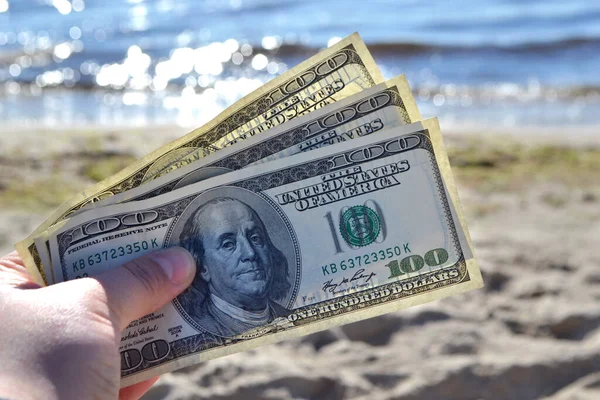 Dollar rekeningen op de achtergrond van de zee en zandstrand in de buurt van de zee op zonnige — Stockfoto