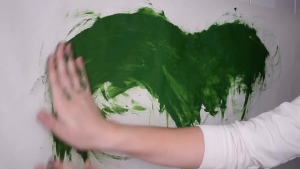 Las manchas de mujer dibujan pintura verde sobre una superficie blanca — Vídeo de stock