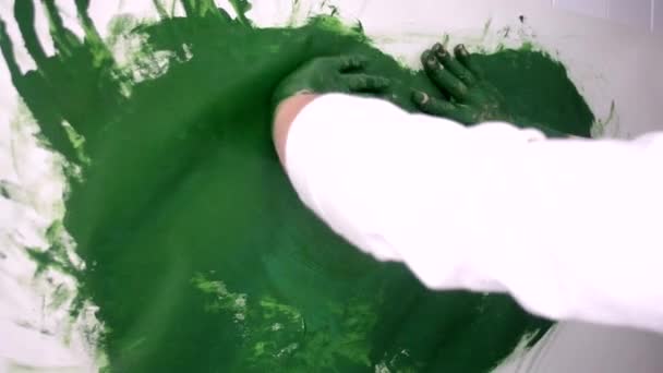 La mujer dibuja una pintura verde mancha sus manos manchadas — Vídeo de stock