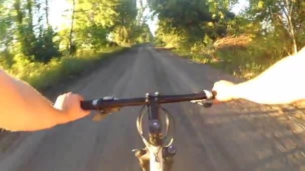 Person riding a cycle on a wide dirt road at dawn sunset — Stock Video