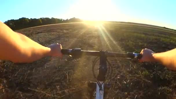 El hombre en bicicleta está viajando a través del campo para encontrarse con el sol durante el amanecer — Vídeos de Stock