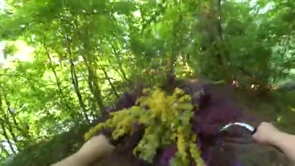 Menina monta uma bicicleta com um buquê de flores na frente da roda — Vídeo de Stock