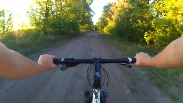 Person riding a cycle on a wide dirt road at dawn sunset — Stock Video