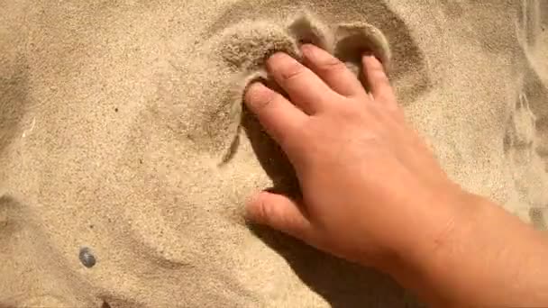 Person runs his hand over surface of sand and scatters it with his fingers — Stock Video