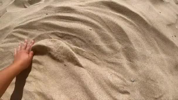 Το άτομο απλώνει το χέρι του πάνω από την επιφάνεια της άμμου και την σκορπίζει με τα δάχτυλά του — Αρχείο Βίντεο