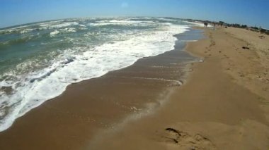 Kumsalın kumlu sahilinde beyaz köpüklü deniz dalgaları. Üst görünüm.