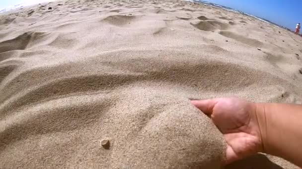 Girl scoops handful of sand in her palm scatters sand through fingers — Stock Video