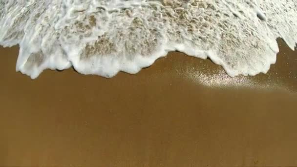 Ola de mar con rollos de espuma blanca sobre la orilla arenosa de la playa. Vista superior. — Vídeo de stock