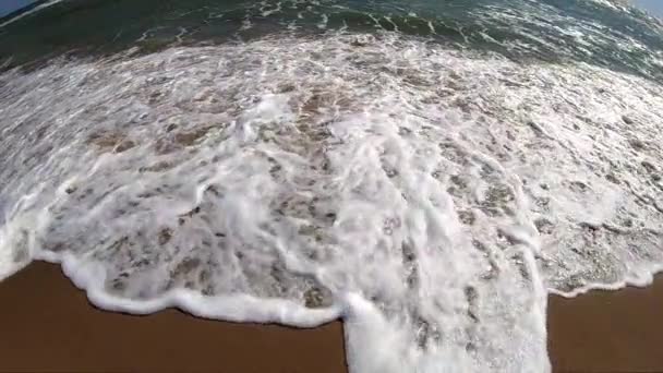 Ola de mar con rollos de espuma blanca sobre la orilla arenosa de la playa. Vista superior. — Vídeo de stock