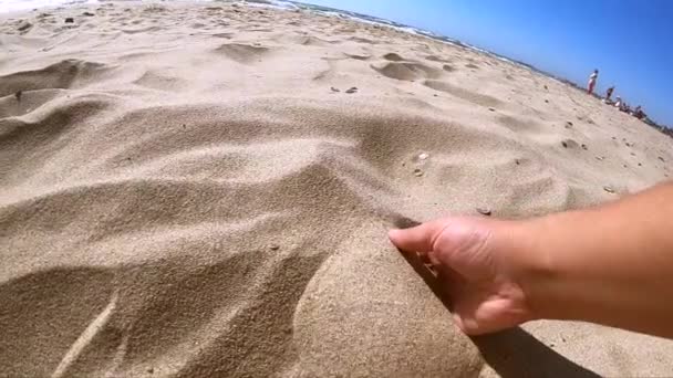 Girl scoops handful of sand in her palm scatters sand through fingers — Stock Video