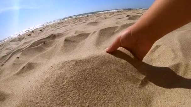 Girl scoops handful of sand in her palm scatters sand through fingers — Stock Video