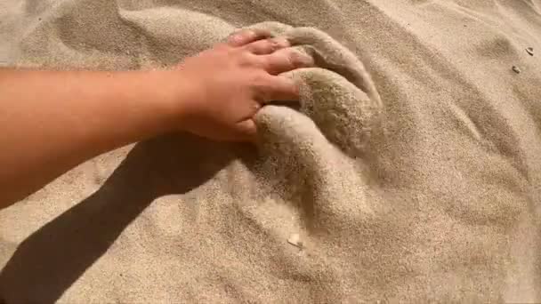 Το άτομο τρέχει το χέρι του πάνω από την επιφάνεια της κίτρινης άμμου, σκορπίζει με τα δάχτυλα — Αρχείο Βίντεο