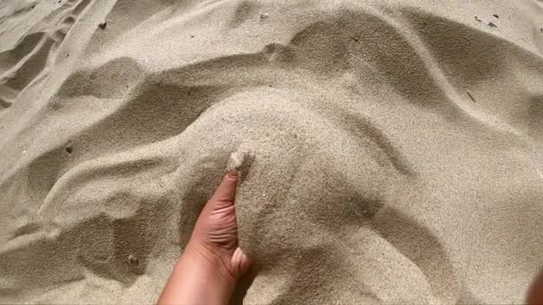 女孩用手拿着一把沙子，用手指撒沙 — 图库视频影像