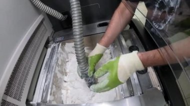 Adam, beyaz plastik tozundan endüstriyel 3D yazıcıya basılmış detayları temizliyor