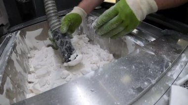 Adam, beyaz plastik tozundan endüstriyel 3D yazıcıya basılmış detayları temizliyor