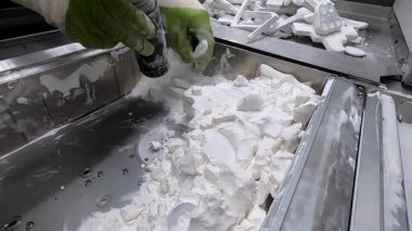 Adam, beyaz plastik tozundan endüstriyel 3D yazıcıya basılmış detayları temizliyor