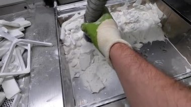 Adam, beyaz plastik tozundan endüstriyel 3D yazıcıya basılmış detayları temizliyor