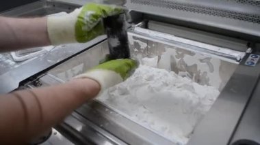 İnsan, endüstriyel 3D yazıcıda beyaz plastik tozundan basılan detayları temizler