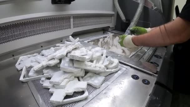 Människan rengör detaljer tryckta på en industriell 3D-skrivare från vitt plastpulver — Stockvideo