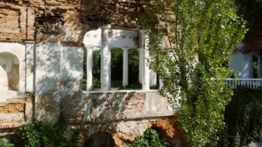 Hava aracı görüntüsü parktaki eski harabelerin arasında kemer şeklinde uçuyor.