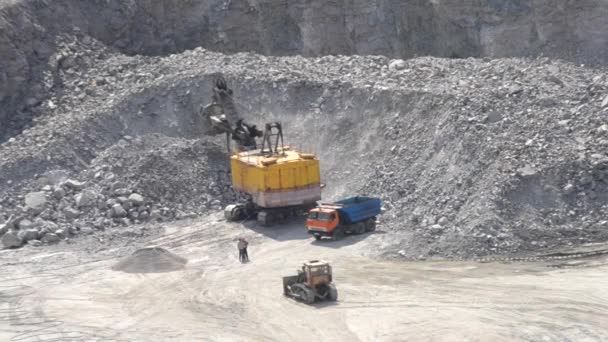 Große riesige gelbe Baggerschaufel hebt große Steine Granit auf und ergießt sich dicht an dicht, — Stockvideo