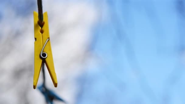 Yellow clothespin hanging on a rope and reeling from the wind — Stock Video