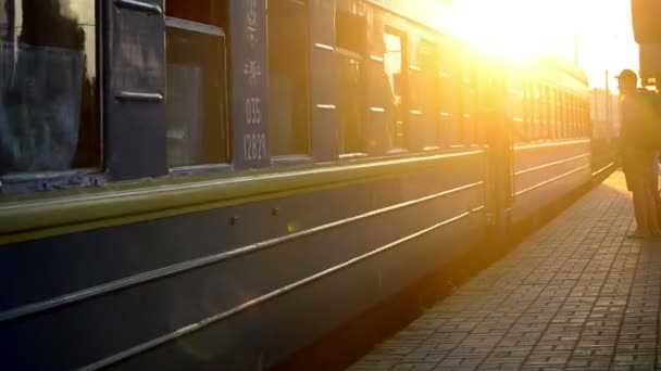En el momento de la puesta del sol tren con vagones azules que salen de la estación de tren — Vídeo de stock