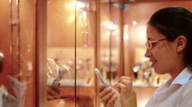 gülümseyerek, mağaza içinde pencere eşiği yanında durup gözlüklü kız