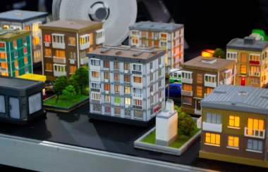 Erimiş plastikten 3D yazıcıya basılan prototip. 3D baskılı bir bina prototipi. Ev, gri duvarlı, gri çatılı ve aydınlatılmış pencere ve balkonlu 3D yazıcıda oluşturuldu.