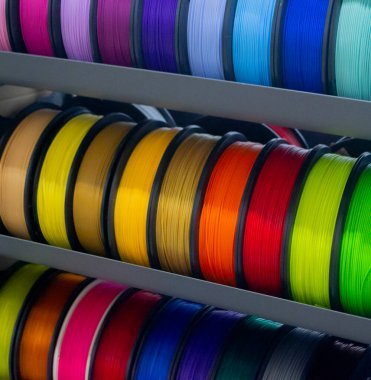 Üç boyutlu basım için çok renkli plastiğe sahip bir sürü makara. 3 boyutlu yazıcı için sarı, turuncu, kahverengi, kırmızı plastik telli makaralar. 3 boyutlu yazdırma için bileşenler. 3D yazıcı için aksesuarlar. FDM teknolojisi